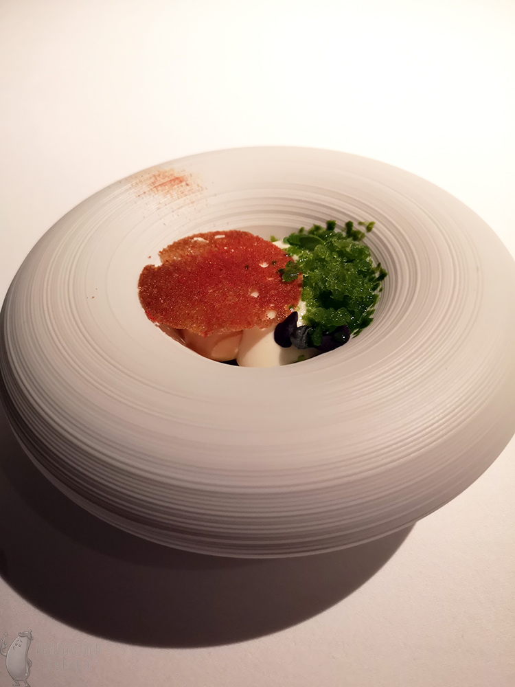 In a round, white tire-like plate, you'll see a fluffy white espuma on which is placed a red disk of gazpacho and next to it is a portion of green basil granita.