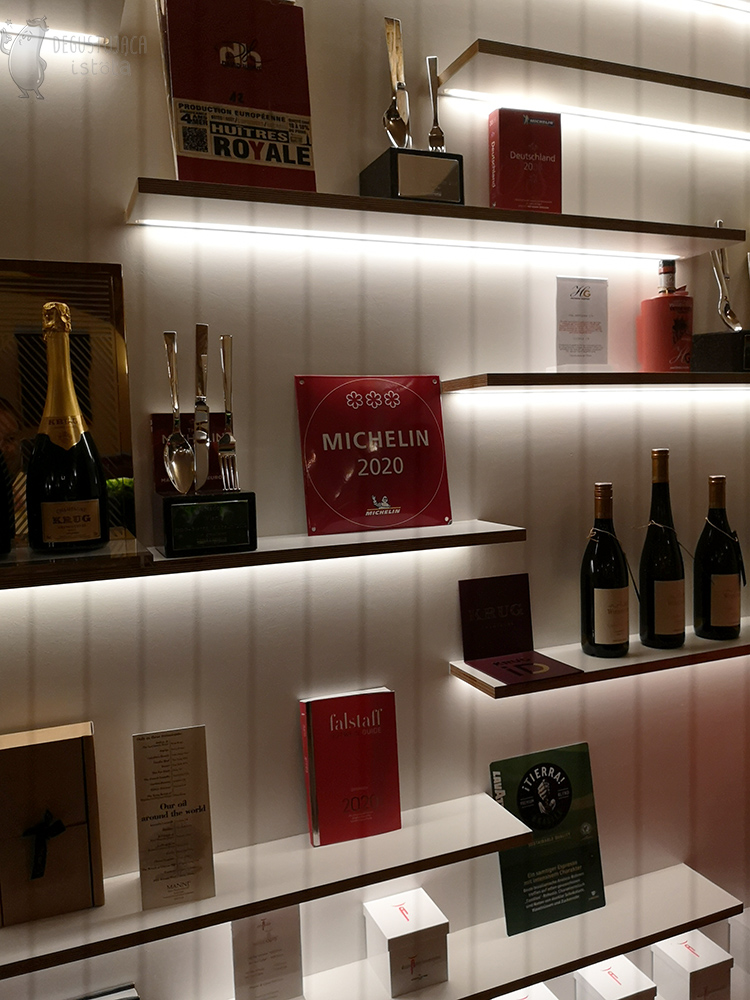 The shelves on which the champagnes stand, guidebooks, cutlery statuettes and a plaque with three Michelin Stars. 