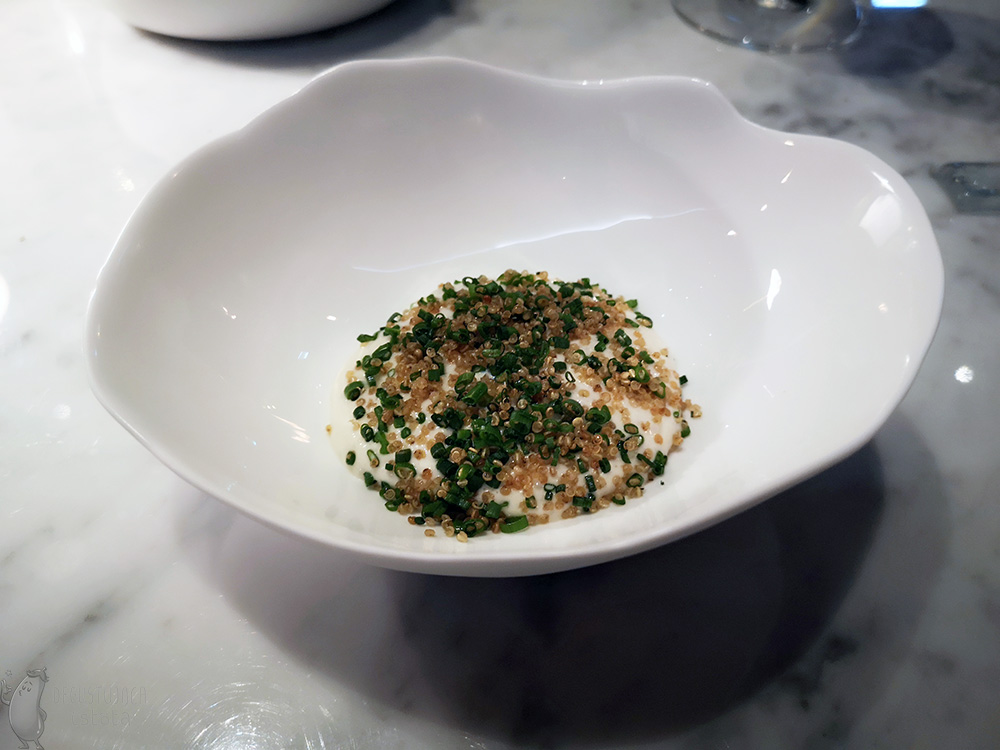 W białym półmisku nałożony jest biały sos z kluseczkami. Posypany jest z wierzchu szczypiorkiem i prażoną komosą ryżową.