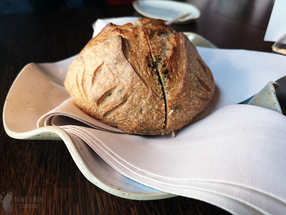 A loaf of bread laid on a white napkin, on a wavy white plate.