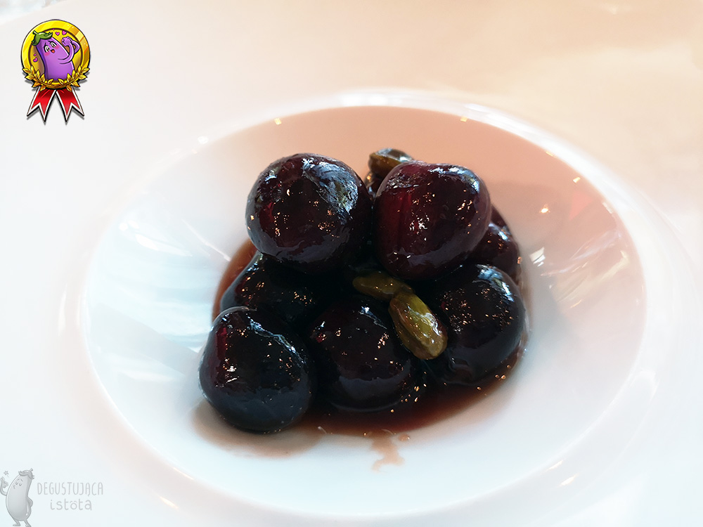 Close-up of cherries with pistachios in a white plate.
