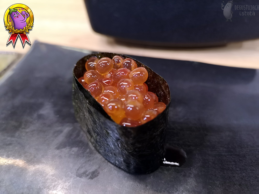 Sushi wrapped in nori algae with a portion of Ikura on top.