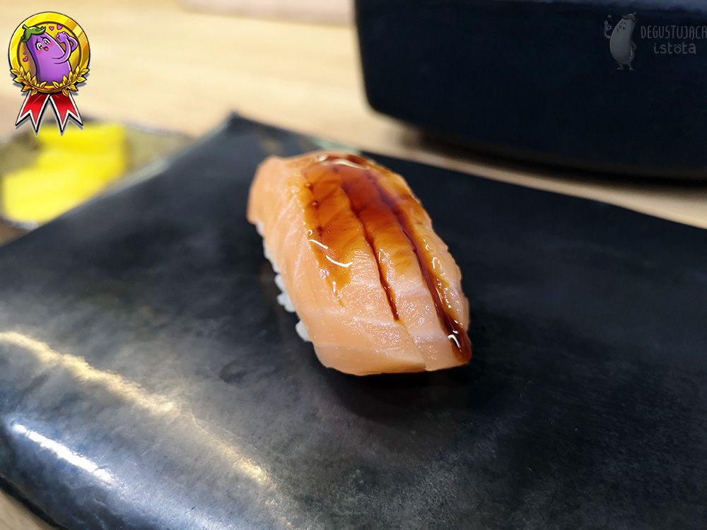 Nigiri with salmon punched on top and topped with sauce.