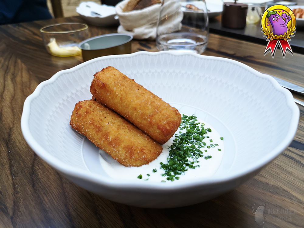 Arranged in a white bowl with cream are 3 thick, breaded polenta fries.