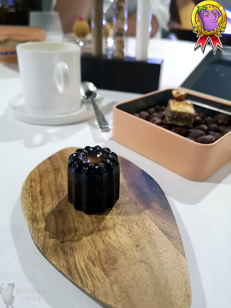 Cookie with dark caramelized crust, which is shaped like a small, ribbed cylinder. Served on a wooden board.