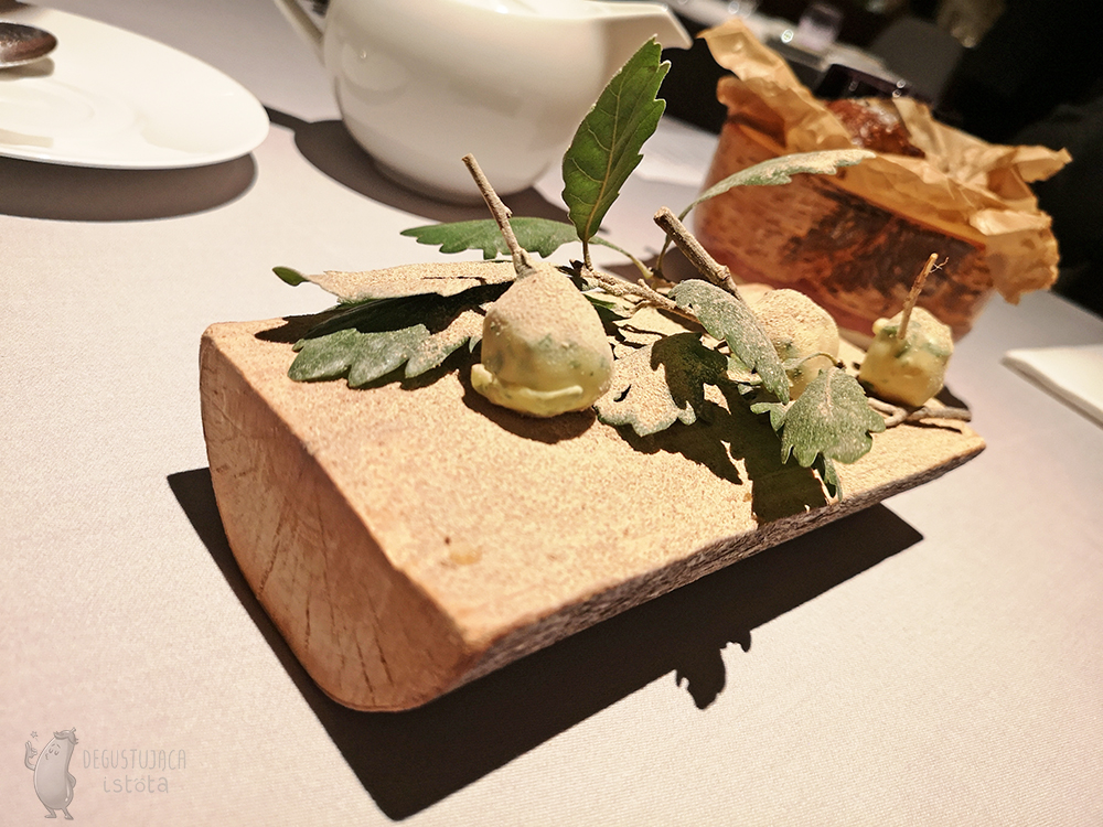 Putt on a wooden block, mini Pears, slightly greenish decorated with leaves and sprinkled with mushroom powder.