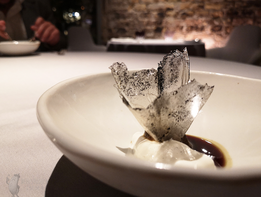 White bowl with crystal potato glass dusted with black powder. On the bottom the cream and sauce was putted.