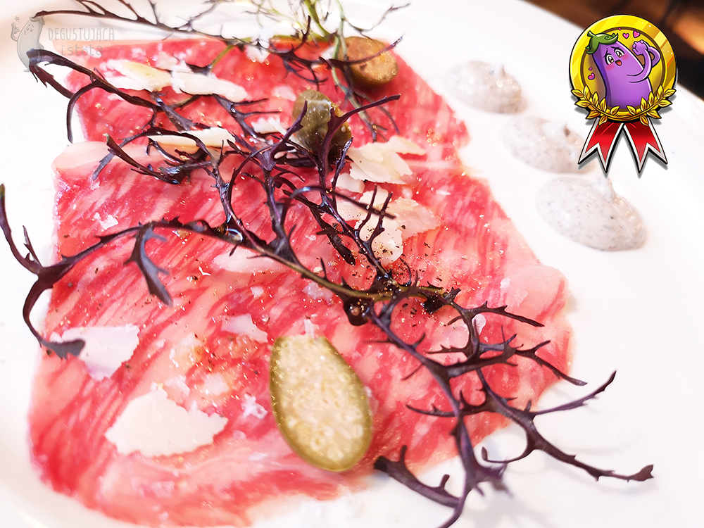 Marbled carpaccio with Wagyu beef with slices of Parmesan cheese and capers.