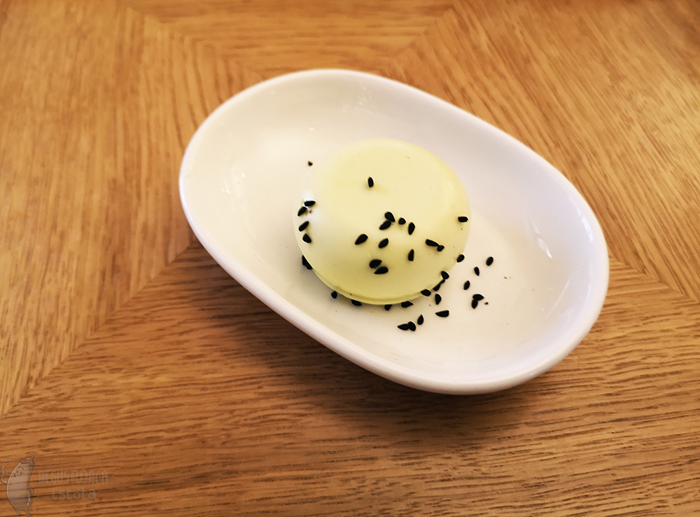 Masło z czarnuszką na białym owalnym talerzyku.