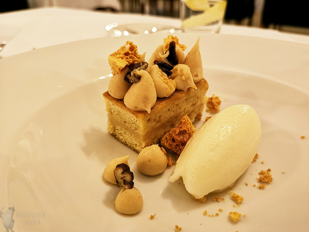A piece of honey cake decorated with pecans and portions of cream. Next to it is a portion of white lemon sorbet.