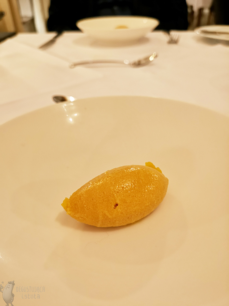 An orange sorbet is placed on white plate.