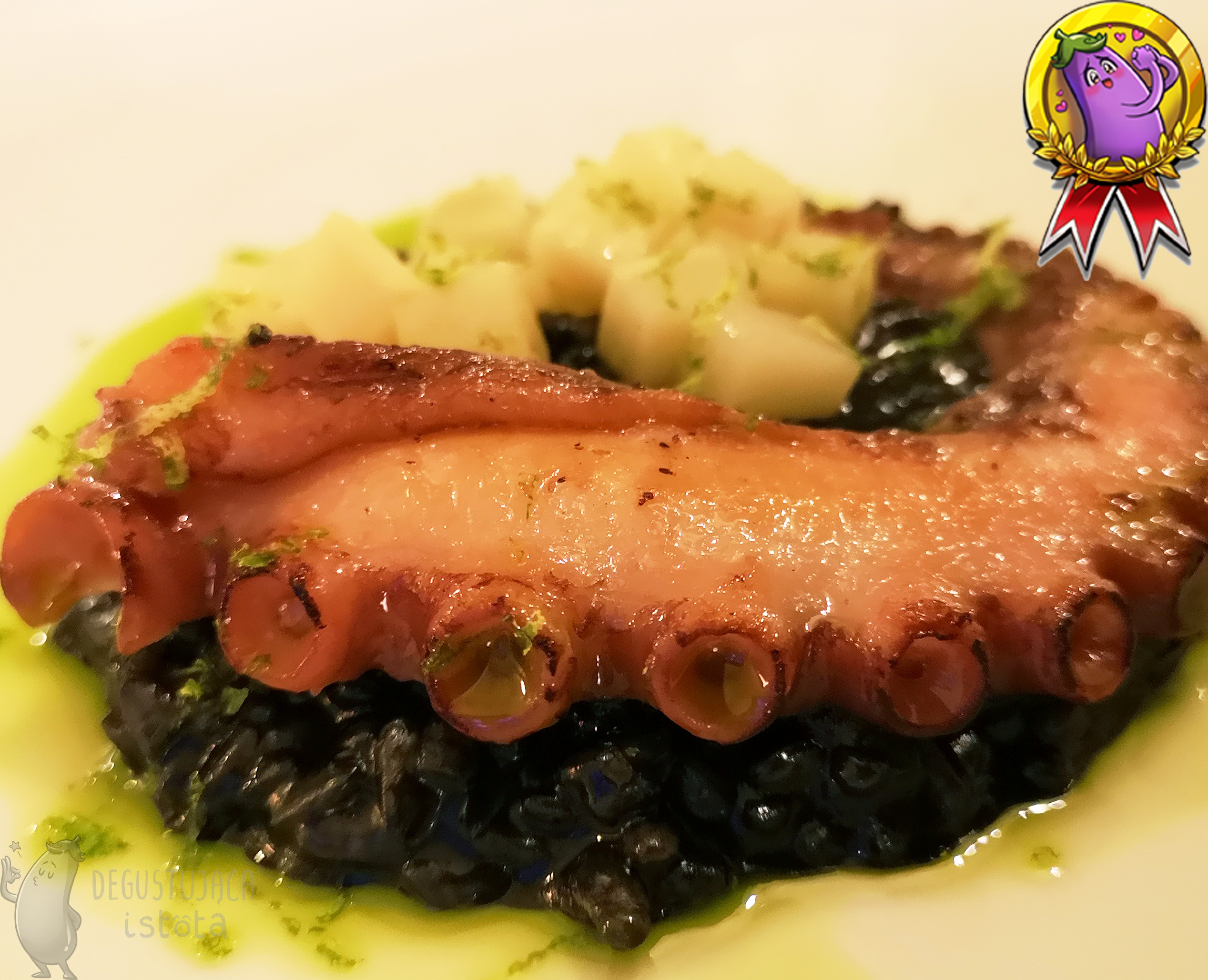Tentacle of octopus on a black risotto. Around it is green olive oil and diced parsley root